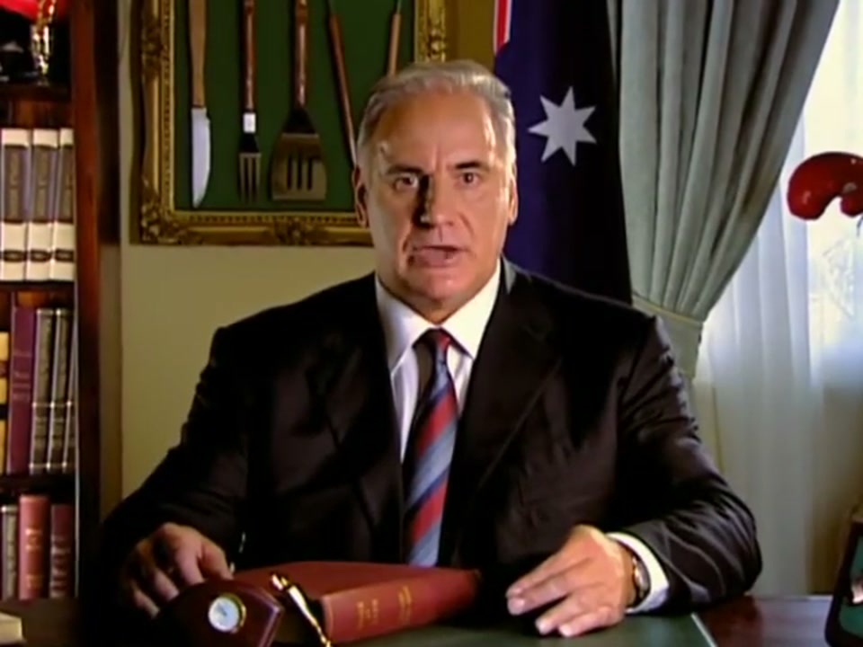 Address to the Nation (2006), scene 3 at 00:53: The camera slowly zooms in on Kekovich's face, increasing the intensity of his address. His expression remains dead serious, adding to the comedic effect of his increasingly absurd list of behaviours.