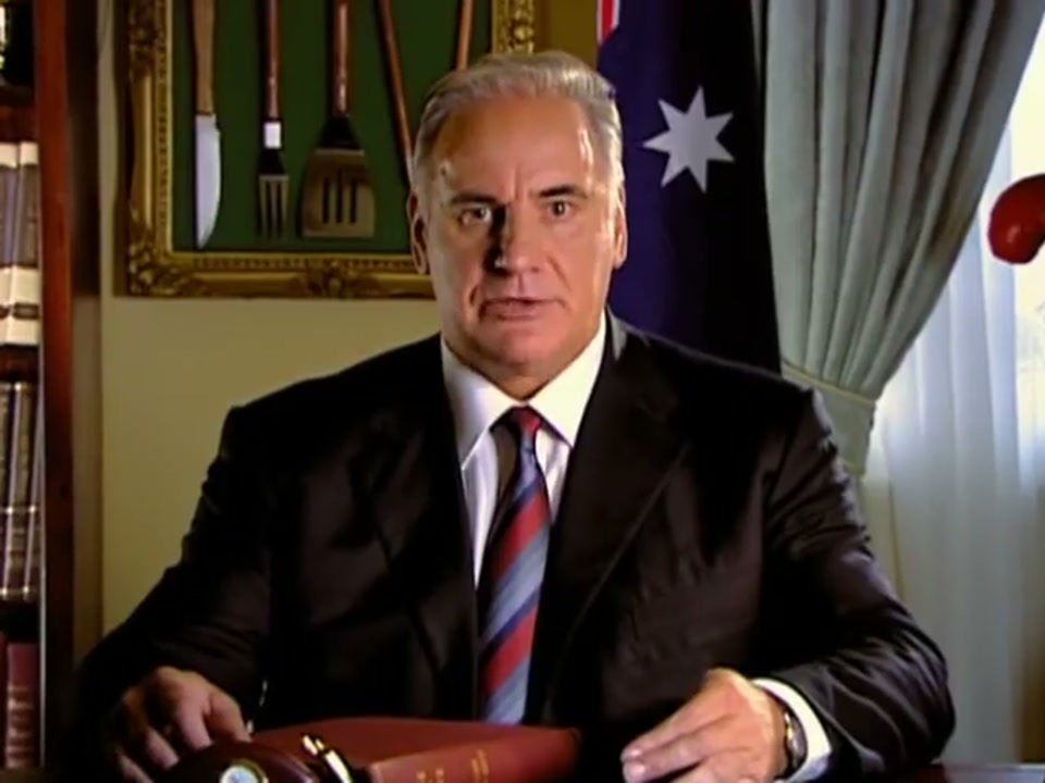 Address to the Nation (2006), scene 3 at 01:00: The camera slowly zooms in on Kekovich's face, increasing the intensity of his address. His expression remains dead serious, adding to the comedic effect of his increasingly absurd list of behaviours.