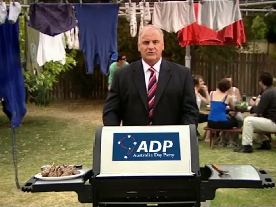 Address to the Nation (Australia Day Party) (2007), scene 6 at 02:23: The speech moves from the formal lectern to a quintessential Australian backyard, with a Hills Hoist clothesline and a barbecue. People are playing backyard cricket in the background.