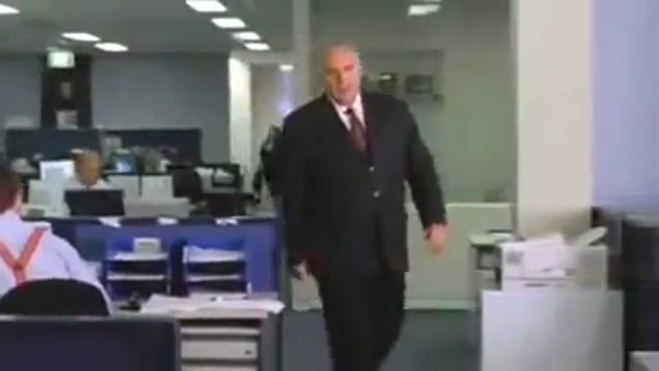 Address to the Nation (GFC Rally) (2009), scene 2 at 00:23: The camera pulls back to reveal the speaker's desk is fronted by a scrolling red-light stock ticker. An Australian flag sits on the desk.