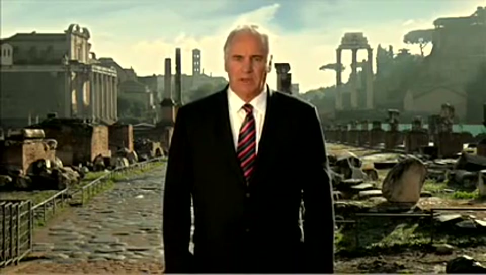 Address to the United Nations of Australia (2011), scene 1 at 00:03: The ad opens on Sam Kekovich, dressed in a dark suit and tie, standing in the middle of the Roman Forum. The lighting is dramatic, suggesting an important historical moment.
