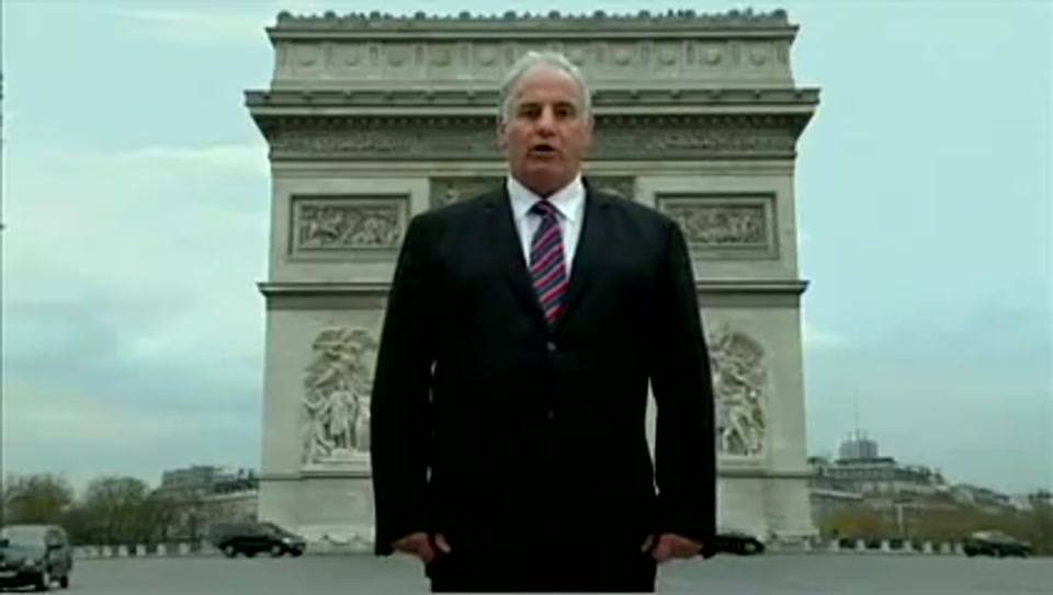 Address to the United Nations of Australia (2011), scene 2 at 00:17: Kekovich stands in a snow-covered English cricket ground, a traditional pavilion in the background. He holds an inflatable cricket bat.