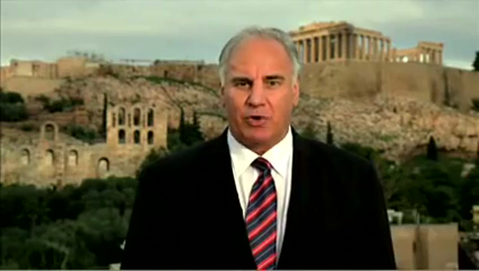Address to the United Nations of Australia (2011), scene 4 at 00:44: Kekovich stands before the Acropolis in Athens. The shot cuts to an extreme close-up of his face, then to a visual joke where he is seen riding a donkey along a beach, led by a local man.