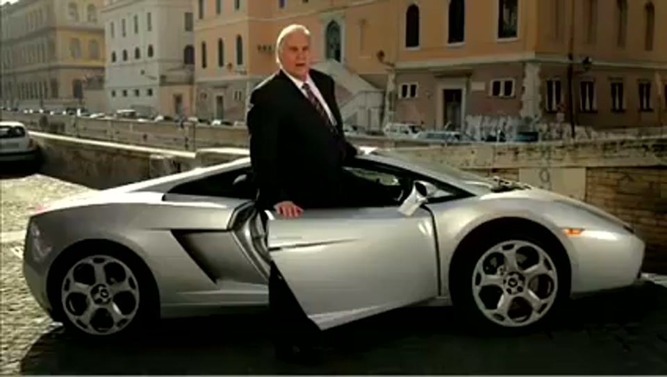 Address to the United Nations of Australia (2011), scene 5 at 00:53: Kekovich stands on the Spanish Steps in Rome. A montage follows: he poses with an attractive woman on a Lambretta scooter, is served Lambrusco wine in a restaurant, and sits in a silver Lamborghini.