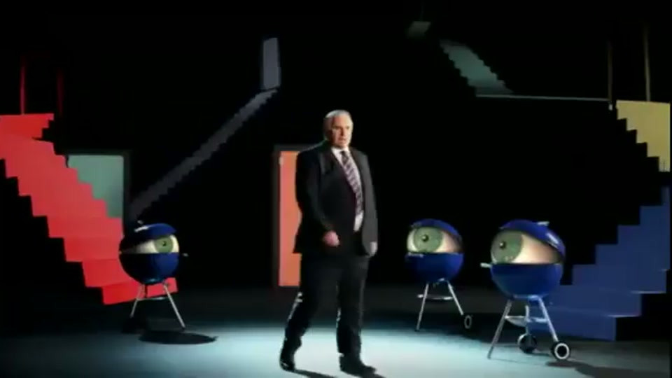 Lambnesia (2013), scene 5 at 00:37: Kekovich, back in his suit, walks through a surreal, M.C. Escher-like space with multiple doors and staircases. He passes several Weber kettle barbecues, which have large, blinking eyeballs under their lids.