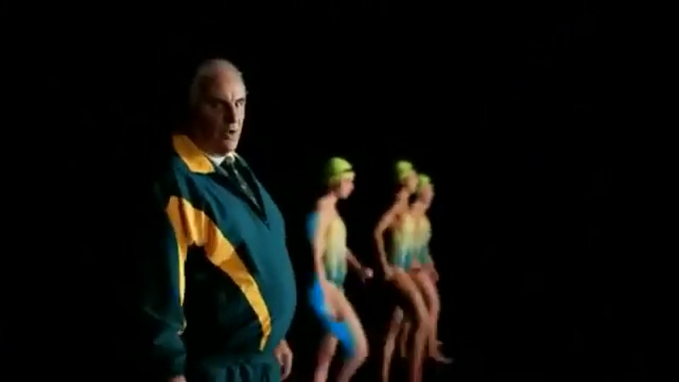 Lambnesia (2013), scene 5 at 00:41: Kekovich, back in his suit, walks through a surreal, M.C. Escher-like space with multiple doors and staircases. He passes several Weber kettle barbecues, which have large, blinking eyeballs under their lids.