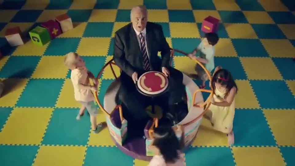 Generation Lamb (2014), scene 2 at 00:13: Kekovich is now seated alone in a spinning teacup ride while four young children run around pushing it. The camera angle is from above.