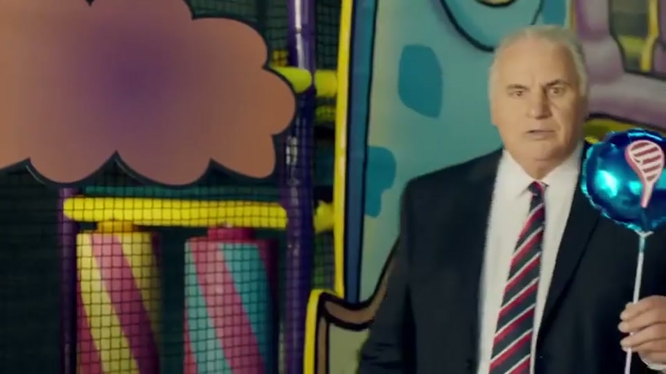 Generation Lamb (2014), scene 2 at 00:16: Kekovich is now seated alone in a spinning teacup ride while four young children run around pushing it. The camera angle is from above.