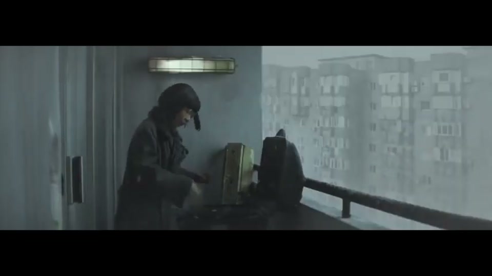 Operation Boomerang (2016), scene 1 at 00:15: The ad opens on a vast, grey, Soviet-era apartment block in a bleak, snowy landscape. The mood is oppressive and cold. A young woman with glasses peers nervously from behind a curtain.
