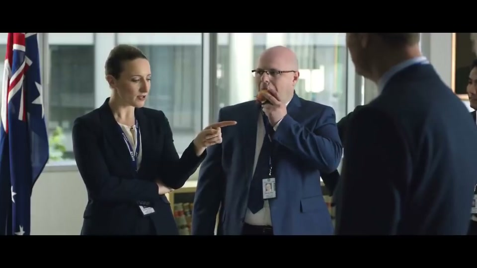 Unite Australia and New Zealand (2019), scene 2 at 00:20: The scene abruptly cuts to a bright, sterile, modern government office. A group of bureaucrats in contemporary suits stand around a table with a similar map. The lead bureaucrat, "Gary," laments Australia's state.