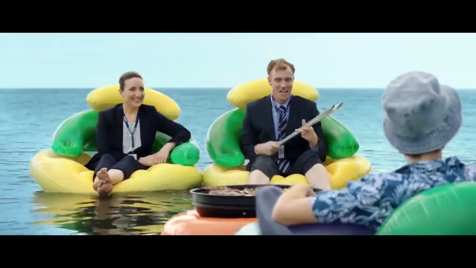Unite Australia and New Zealand (2019), scene 3 at 00:52: The scene shifts to the open ocean. A small charcoal barbecue on an orange inflatable ring floats on the water, sizzling with lamb chops and skewers.