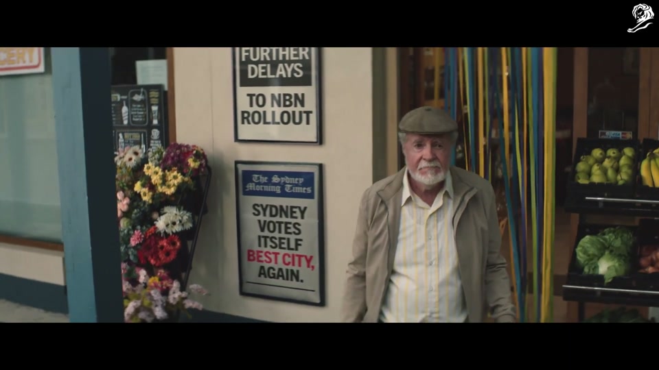 Make Lamb Not Walls (2021), scene 1 at 00:20: The ad opens with a man on a ladder using a paint roller to apply black paint to a colossal concrete wall that stretches to the horizon. The on-screen text "NEW SOUTH WALL" is stencilled onto it.