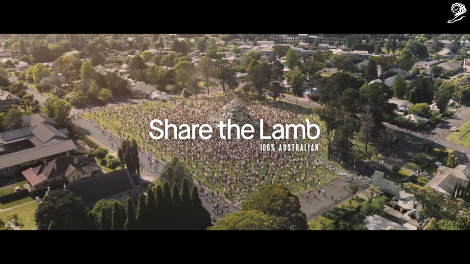 Make Lamb Not Walls (2021), scene 5 at 02:25: The crowd celebrates together, holding lamb chops. A chef stands on a pile of rubble, barbecuing. A young girl, smiling, tells the old man, "We did it." He smiles back, holding his lamb chop.